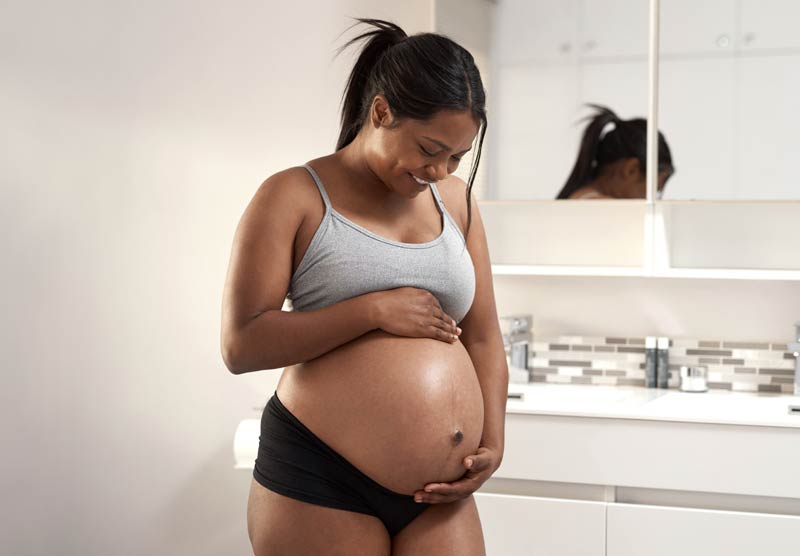 Femme enceinte touche son ventre.