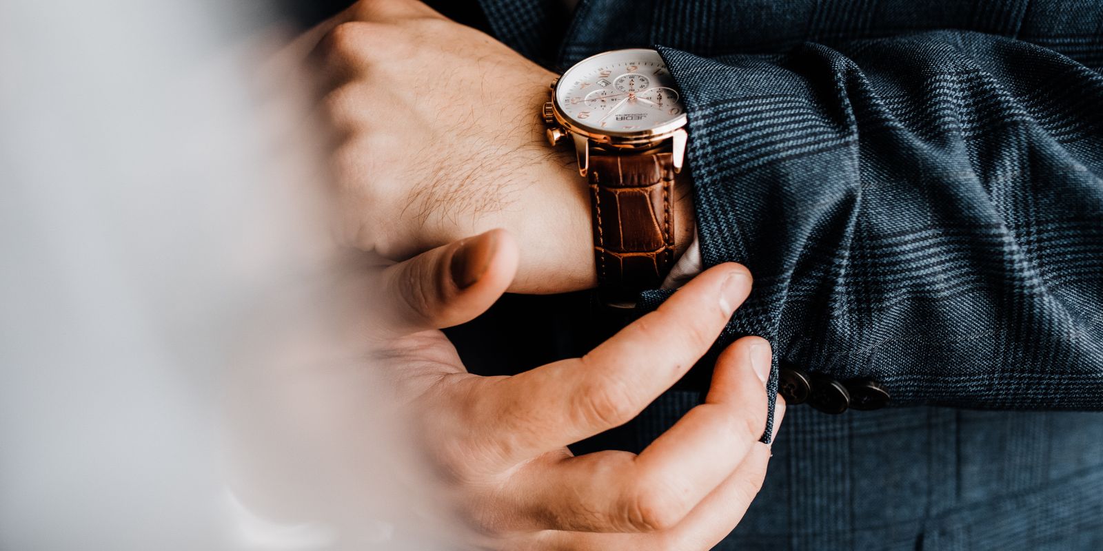 Poignet masculin avec une montre élégante à bracelet en cuir, détail essentiel d’une élégance masculine intemporelle.