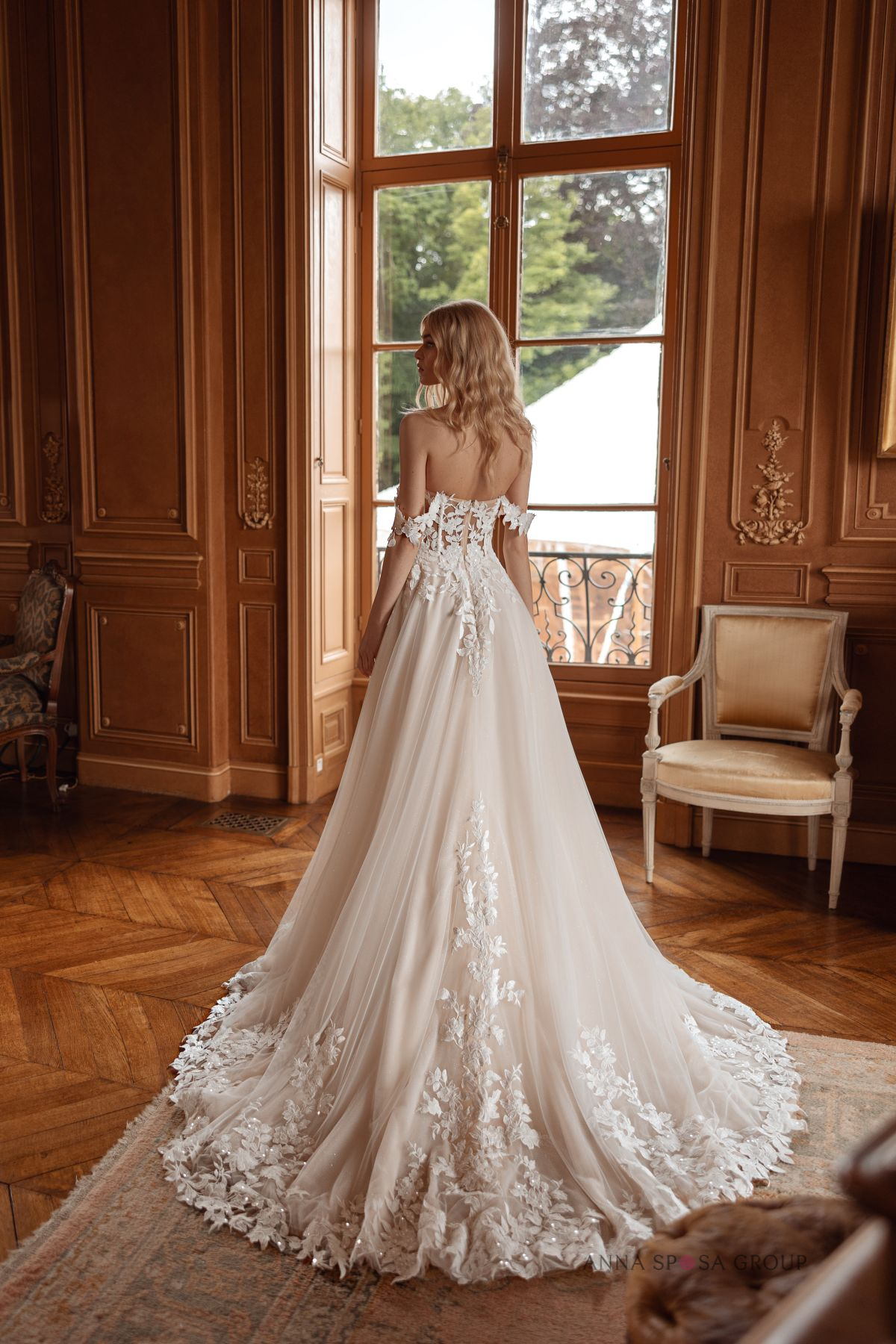 Robe de mariée princesse en tulle et dentelle florale, avec un dos nu délicat et un long voile de motifs 3D. Photographiée dans un intérieur élégant, cette création met en valeur le style romantique des robes de mariée sur mesure.
